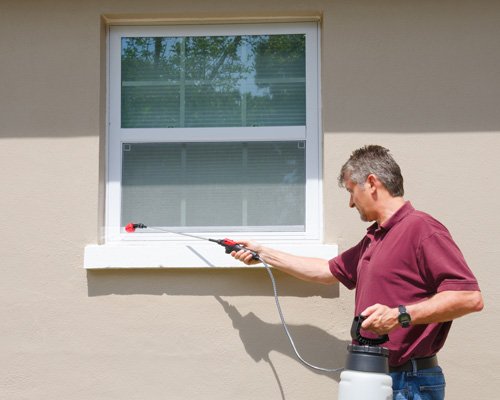 Man spraying window sill outdoor
